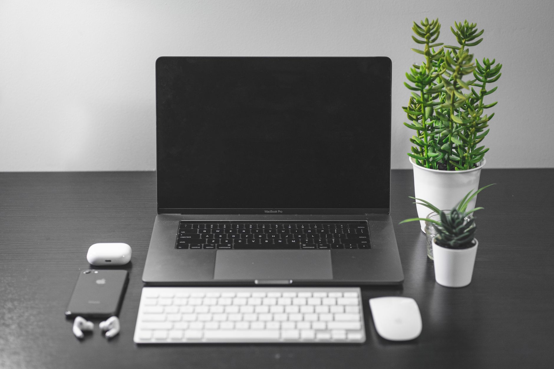 Mesa organizada com laptop, smartphone e plantas, representando um ambiente de trabalho digital moderno