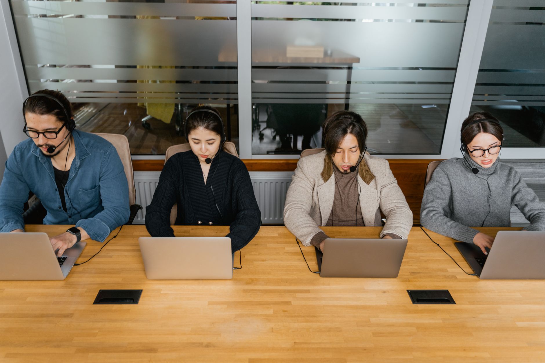 Grupo de atendentes com fones de ouvido trabalhando em laptops em um escritório moderno