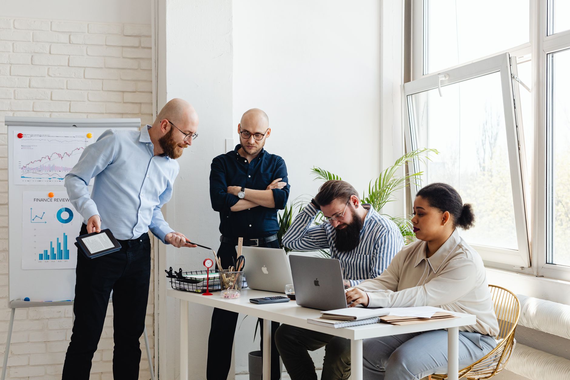 Equipe diversa discutindo estratégia em escritório moderno com laptops e gráficos